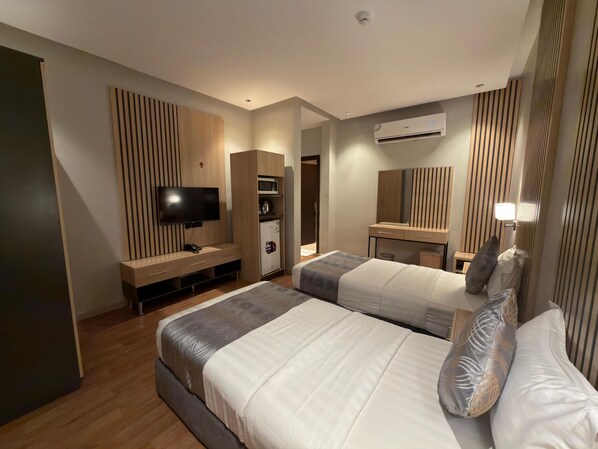 A modern hotel room with two beds, a flat-screen TV, a minibar, and a large mirror. - السعاده سويت للشقق المخدومه (Riyadh)