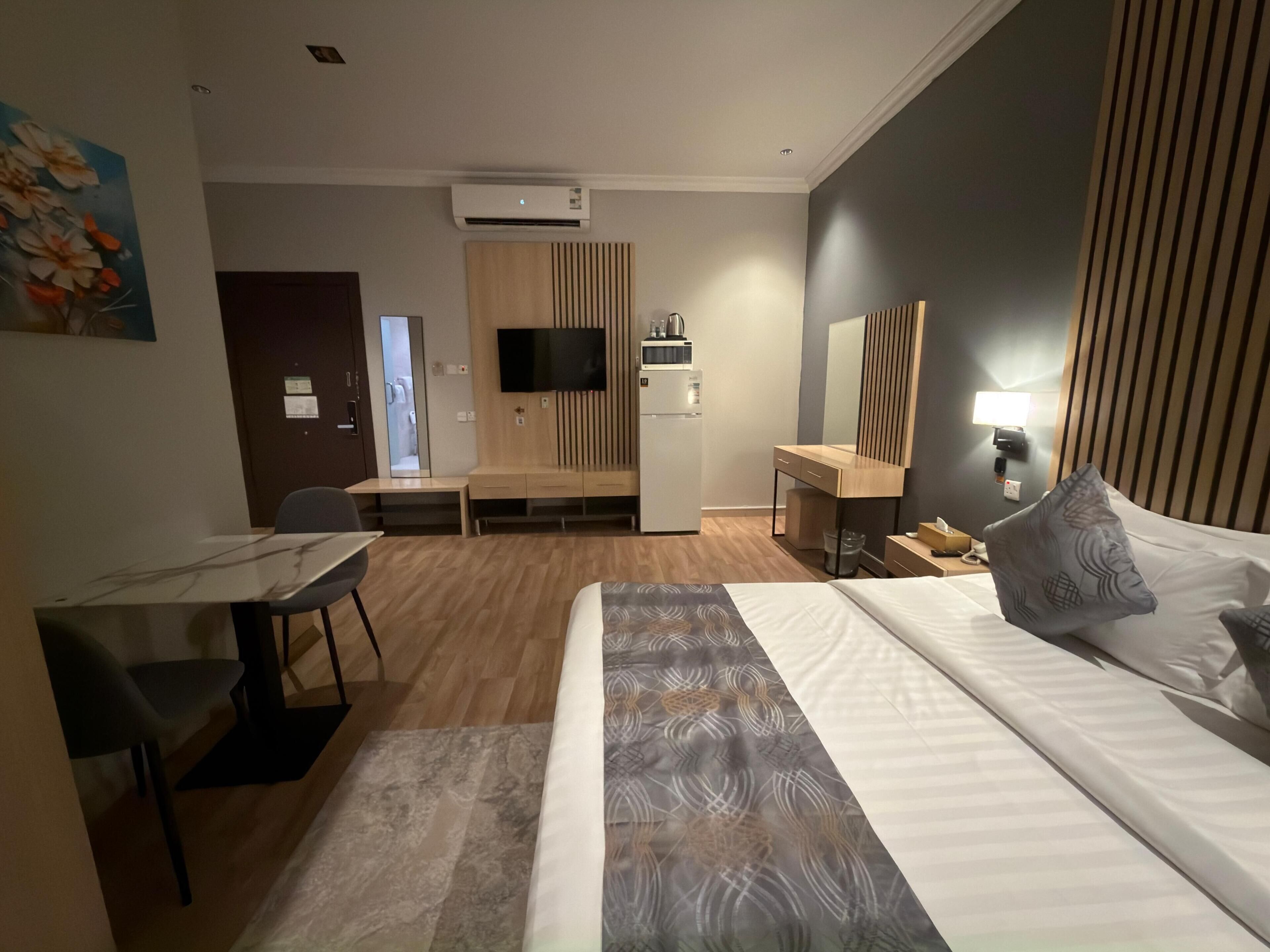 Una camera d'albergo con un letto, una scrivania, una sedia, una TV e un angolo cottura.
