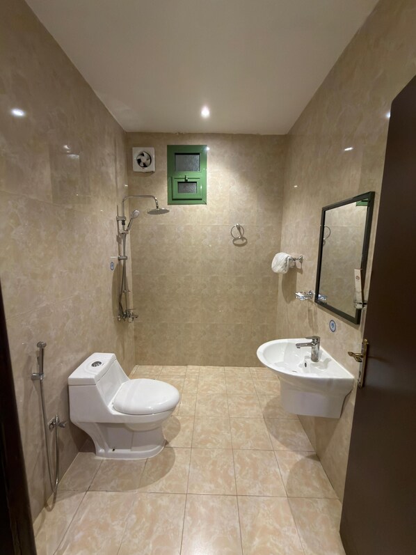 A bathroom with a toilet, sink, and shower. - السعاده سويت للشقق المخدومه (Riyadh)