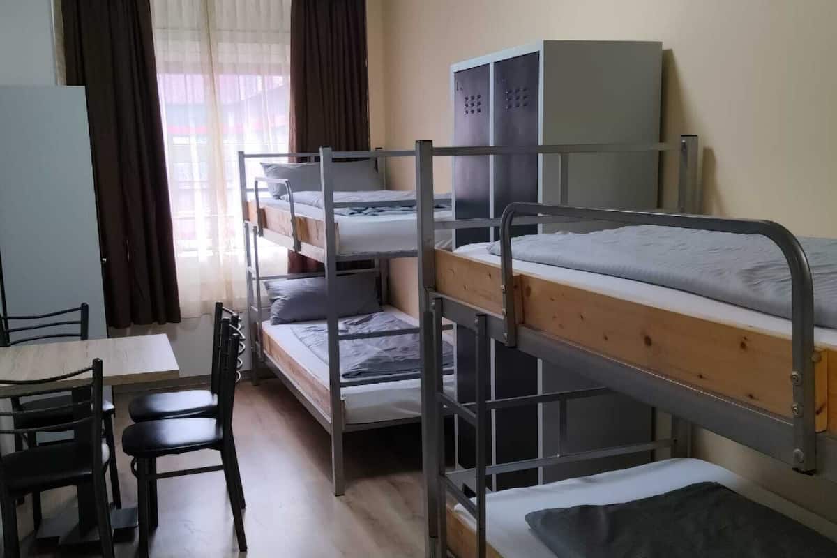 Een slaapzaal met stapelbedden, een bureau, stoelen en een kledingkast.