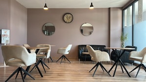 A modern interior with round tables, chairs, and two wall-mounted clocks. - Sitya Hostel München (Munich)