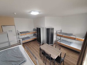 A dormitory room with bunk beds, a table, chairs, a wardrobe, and a desk. - Sitya Hostel München (Munich)