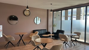 A modern interior with round tables, leather sofas, and large mirrors. - Sitya Hostel München (Munich)