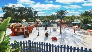 Een waterpark met een piratenschip, glijbanen en een zandstrand.