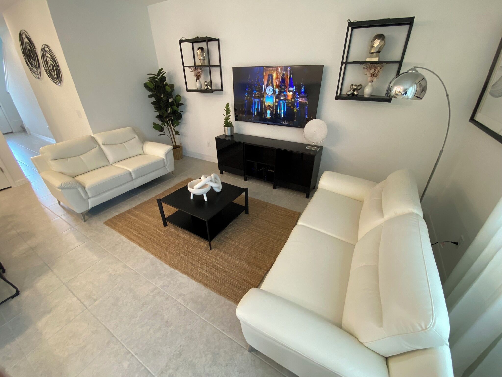 Ein modernes Wohnzimmer mit einem weißen Sofa, einem schwarzen Couchtisch und einem Fernseher auf einem schwarzen Schrank.