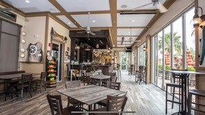 En rummelig restaurant med trægulv, store vinduer og et barområde.