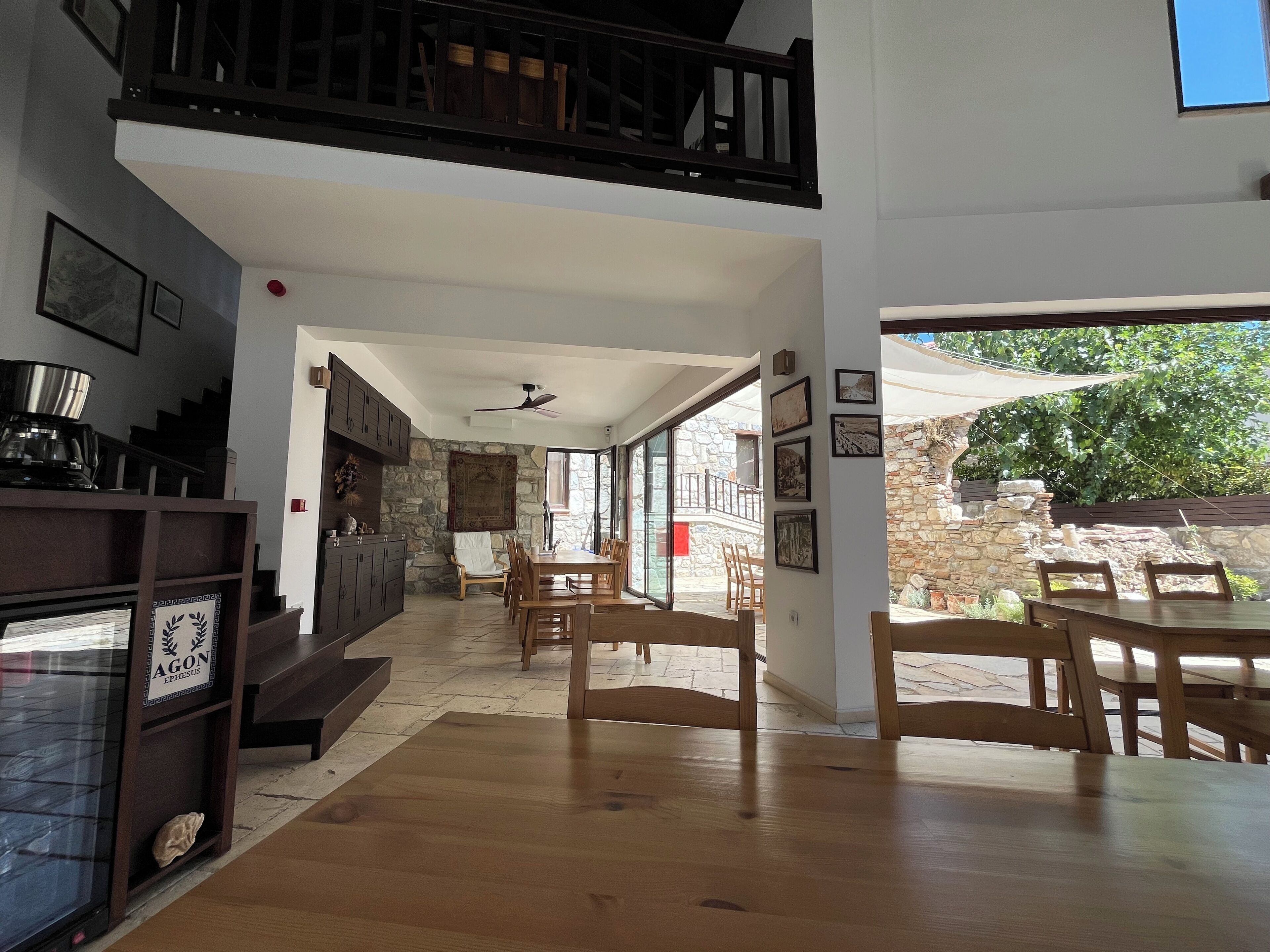 A spacious interior with a dining area, wooden furniture, a staircase, and a stone wall.
