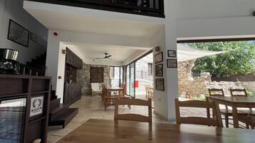 A spacious interior with a dining area, wooden furniture, a staircase, and a stone wall.