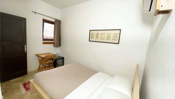 Una camera da letto con un letto, una scrivania, una sedia, una finestra con tende e un quadro appeso al muro.
