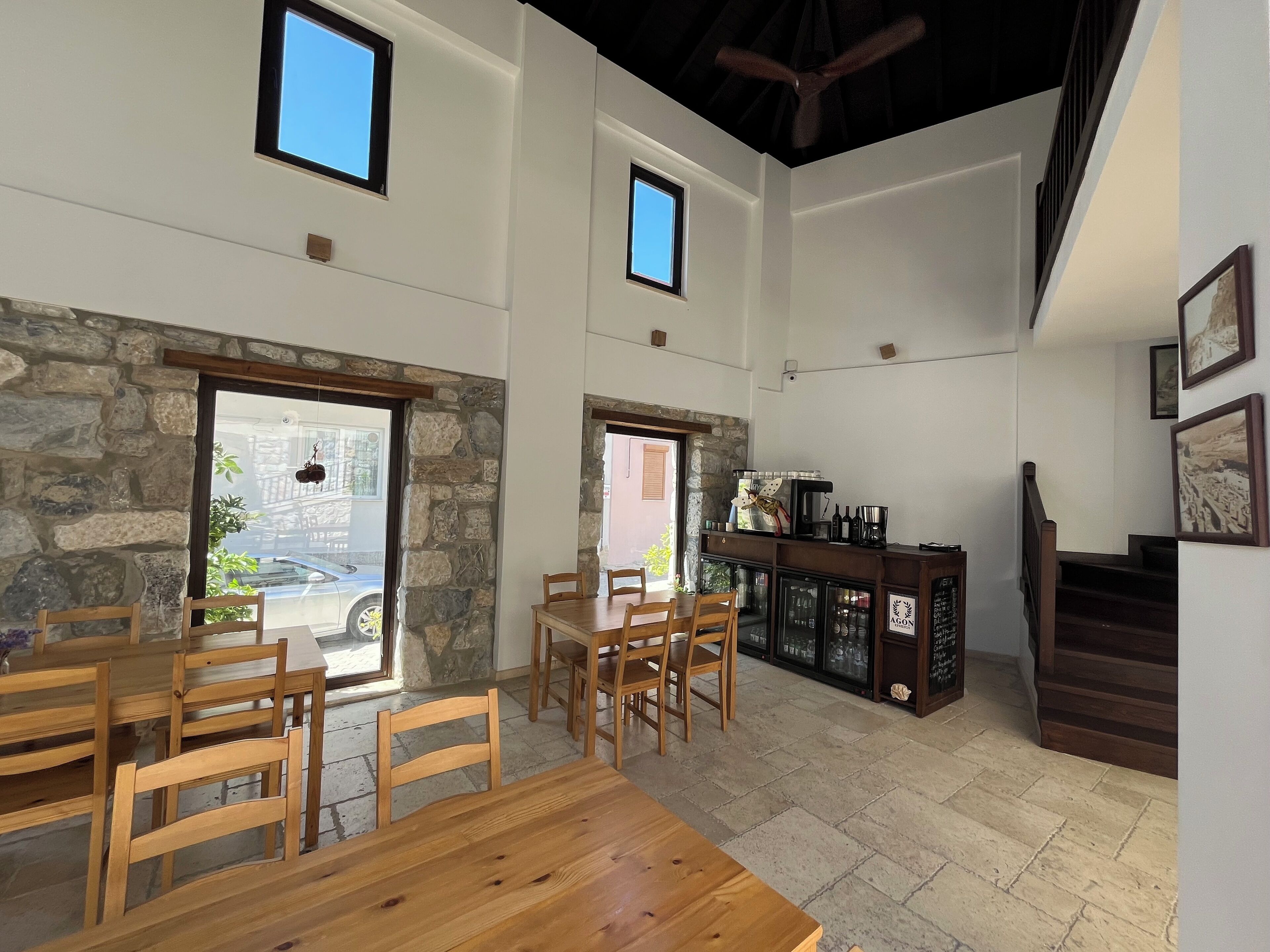 A spacious room with a stone wall, wooden furniture, a bar area, and a staircase.