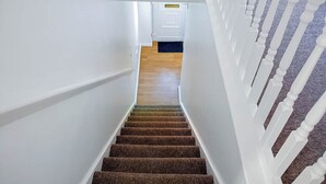 A staircase with a patterned carpet leading to a room with a white door. - Airport Lounge - 3Bed 6 Persons (Manchester)