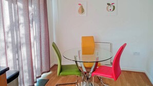 A dining area with a glass table, four chairs, a red hanging light, and two wall art pieces. - Airport Lounge - 3Bed 6 Persons (Manchester)
