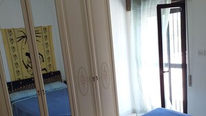 A bedroom with a bed, a wardrobe, and a window with curtains.