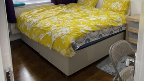 Une chambre à coucher avec un lit, une chaise, un radiateur et une fenêtre avec des rideaux.