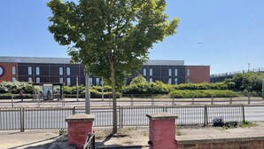 Un bâtiment moderne avec une façade en briques, un trottoir pavé et une clôture en métal.