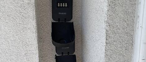 Un dispositivo de seguridad fijado a la pared con un mecanismo de cierre y un cable conectado.