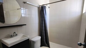 Un baño con inodoro, lavamanos y zona de ducha.
