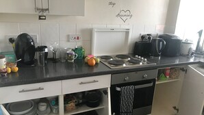 Ett kök med vita skåp, en spis, en kaffebryggare och diverse köksredskap på bänkskivan.