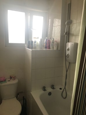 A bathroom with a toilet, a bathtub, a shower, and a window.