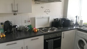 Ett modernt kök med vita skåp, en spis, en kaffebryggare och en tvättmaskin.