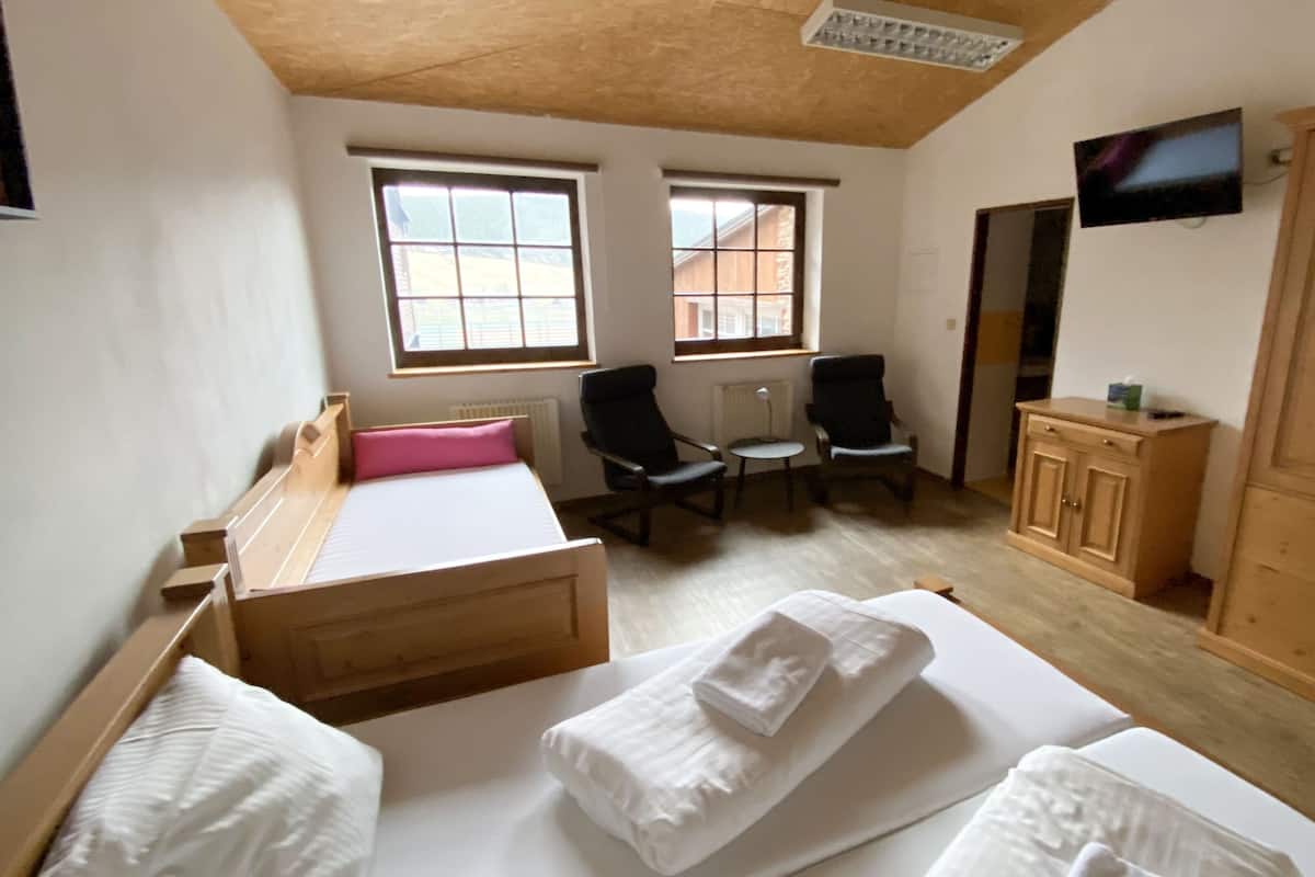 A room with two beds, a small table, two chairs, a TV, and a wardrobe.