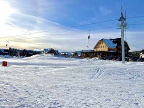 A ski resort with a wooden building, ski lift, and snow-covered landscape. - Wellness Resort Bouda Malá Úpa (Mala Upa)