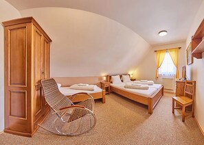 A bedroom with two single beds, a wooden wardrobe, a wicker chair, and a desk with a chair. - Wellness Resort Bouda Malá Úpa (Mala Upa)