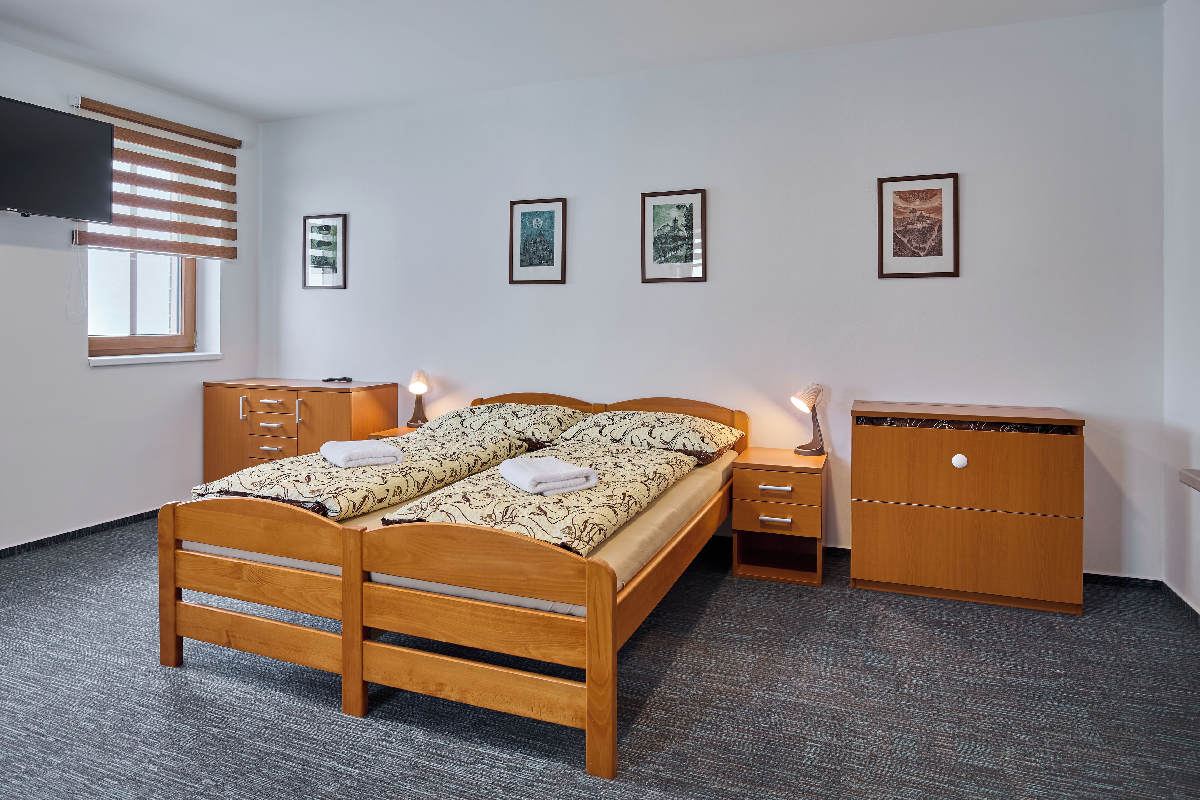 Un dormitorio con una cama de madera, mesitas de noche, un armario y cuadros enmarcados en la pared.