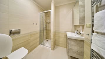A bathroom with a toilet, sink, and shower area.