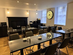 A conference room with multiple tables and chairs, a fireplace, and a large wall clock. - Arran House Hotel (London)
