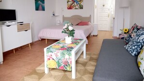 A well-lit, modern bedroom with a bed, bedside table, and a TV on a stand.