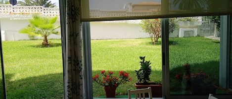 A room with a large window overlooking a well-maintained lawn and garden.
