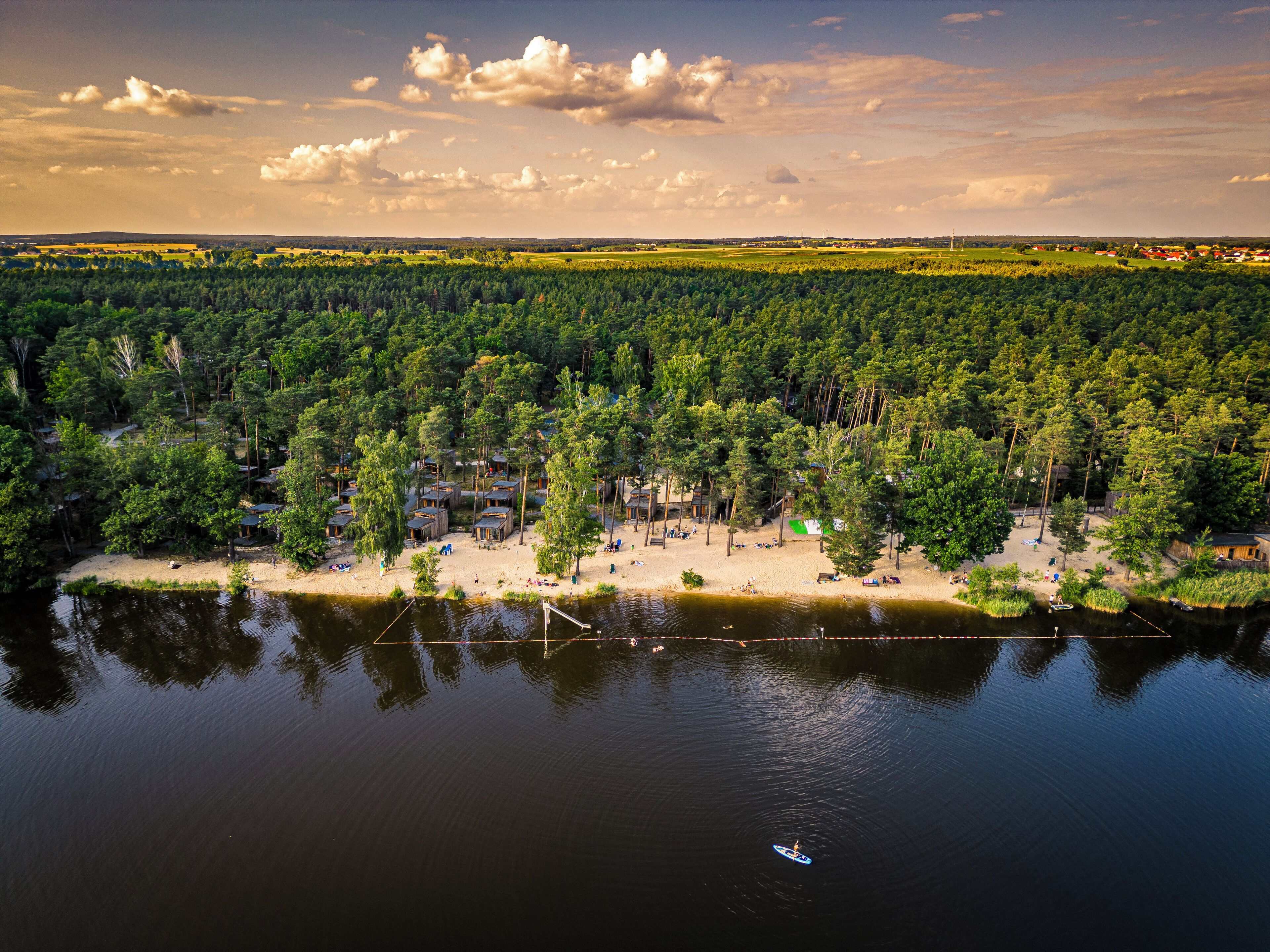 Resort na margem do lago com cabanas e uma área de praia de areia.