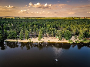 A lakeside resort with cabins and a sandy beach area. - Naturcamping Brettmühlenteich e.G. (Thiendorf)
