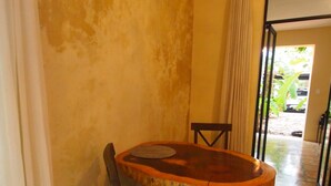 A dining area with a round table, two chairs, and a curtain. - Encantadora Suite, en la Mejor Zona de Paseo Montejo. En el Barrio Gastronómico (Mérida)