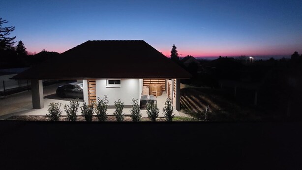 A modern house with a covered porch, a car parked in front, and a clear view of the sky. - Vitorlás apartman 2
 (Balatonszárszó)