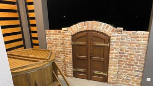 A wooden hot tub with a ladder, a brick wall, and a wooden door. - Vitorlás apartman 2
 (Balatonszárszó)