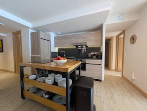 Eine moderne Küche mit Holzausbau, einem schwarzen Kühlschrank und einem Holzespeisetisch mit einer Schüssel Obst.