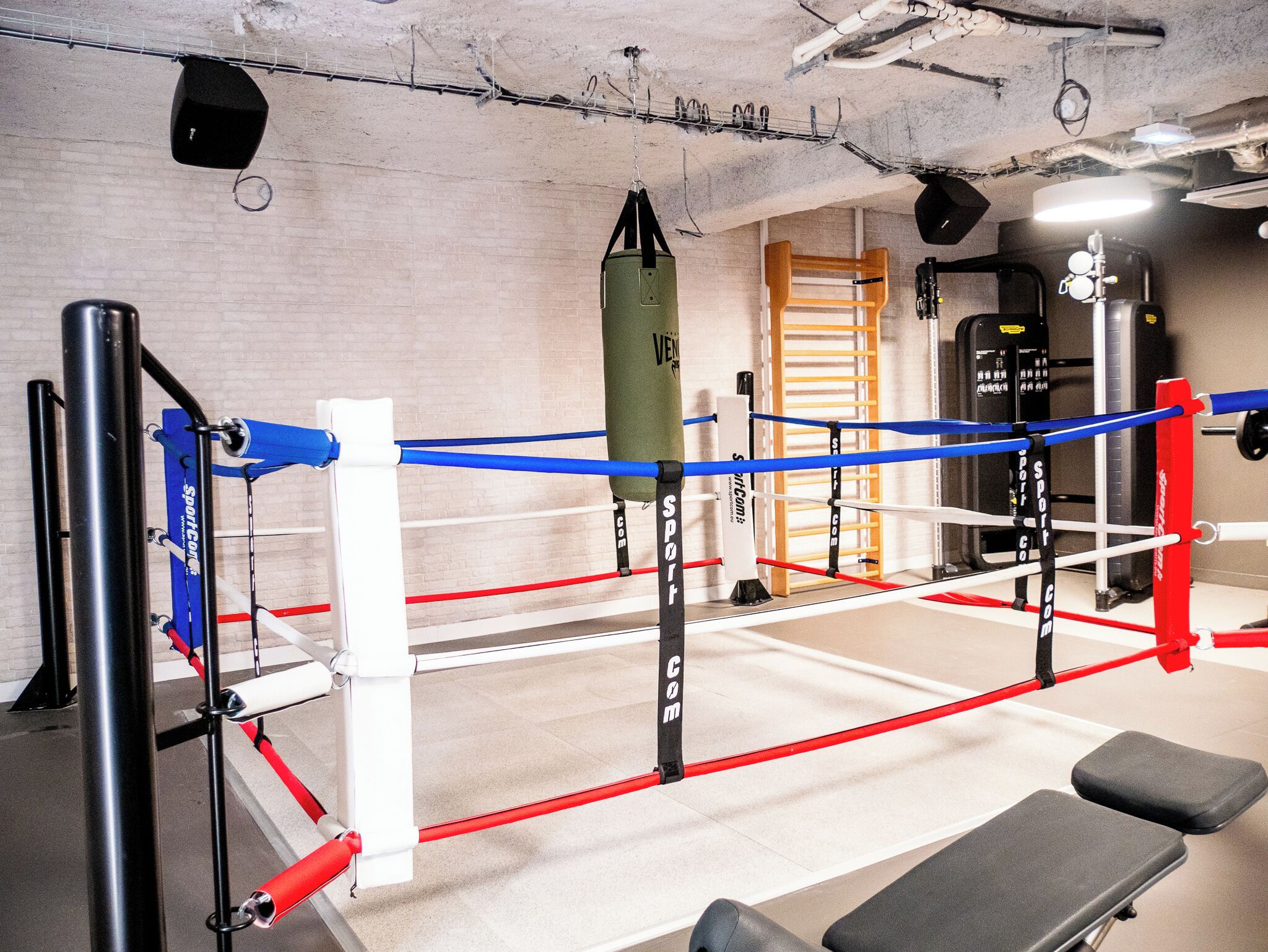 A boxing ring with ropes, corner pads, and a punching bag.