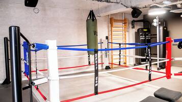 A boxing ring with ropes, corner pads, and a punching bag.