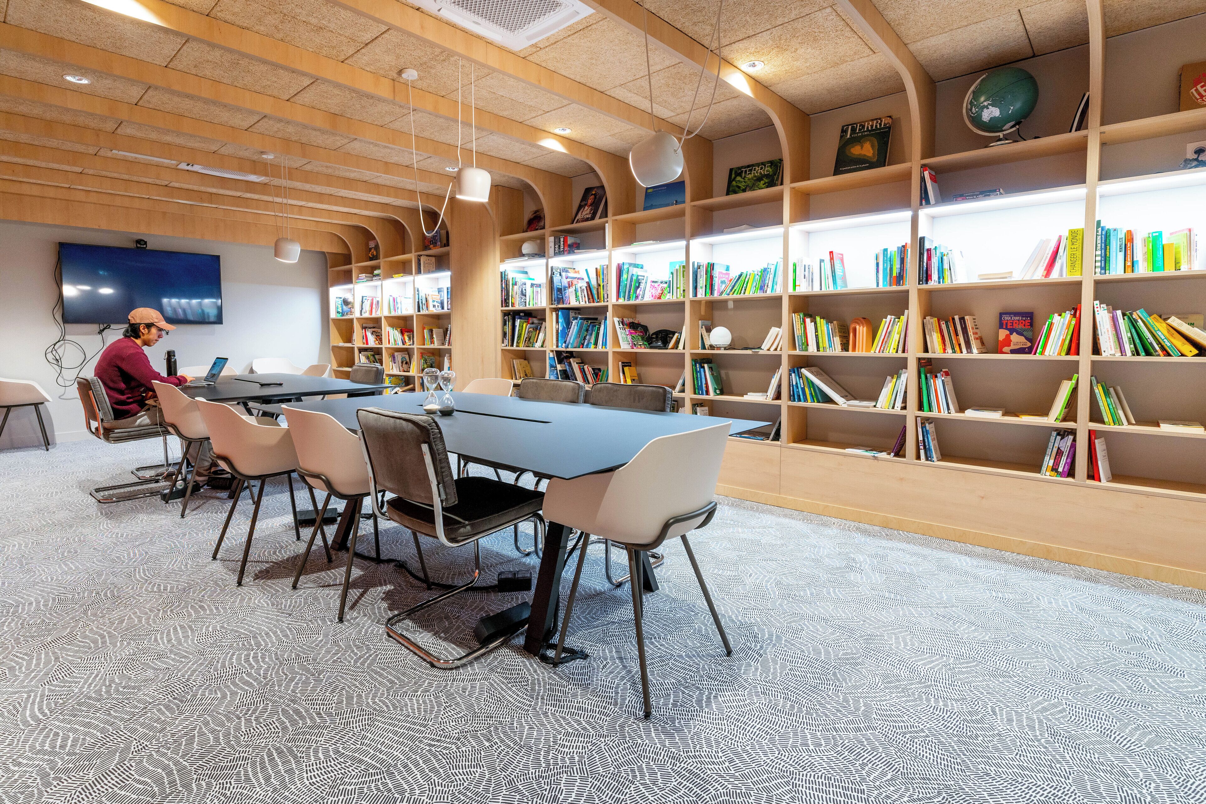 A library with a long table and chairs, surrounded by bookshelves filled with books.