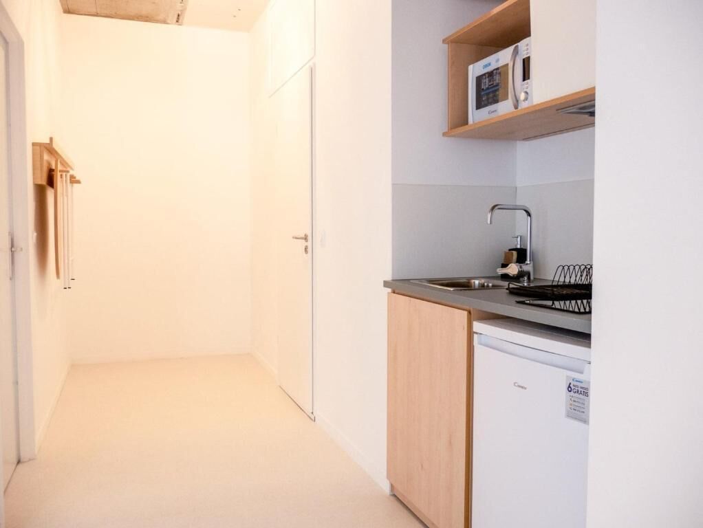 Ett kompakt kök med diskmaskin, mikrovågsugn och diskho.