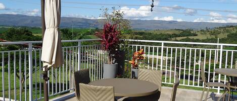 Un patio al aire libre con una mesa redonda y sillas, una planta en maceta y una sombrilla.