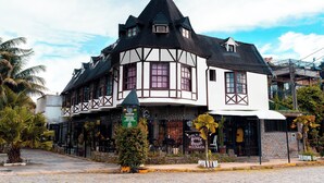 Un edificio tradicional con techo negro y paredes blancas, que cuenta con un balcón y un letrero.