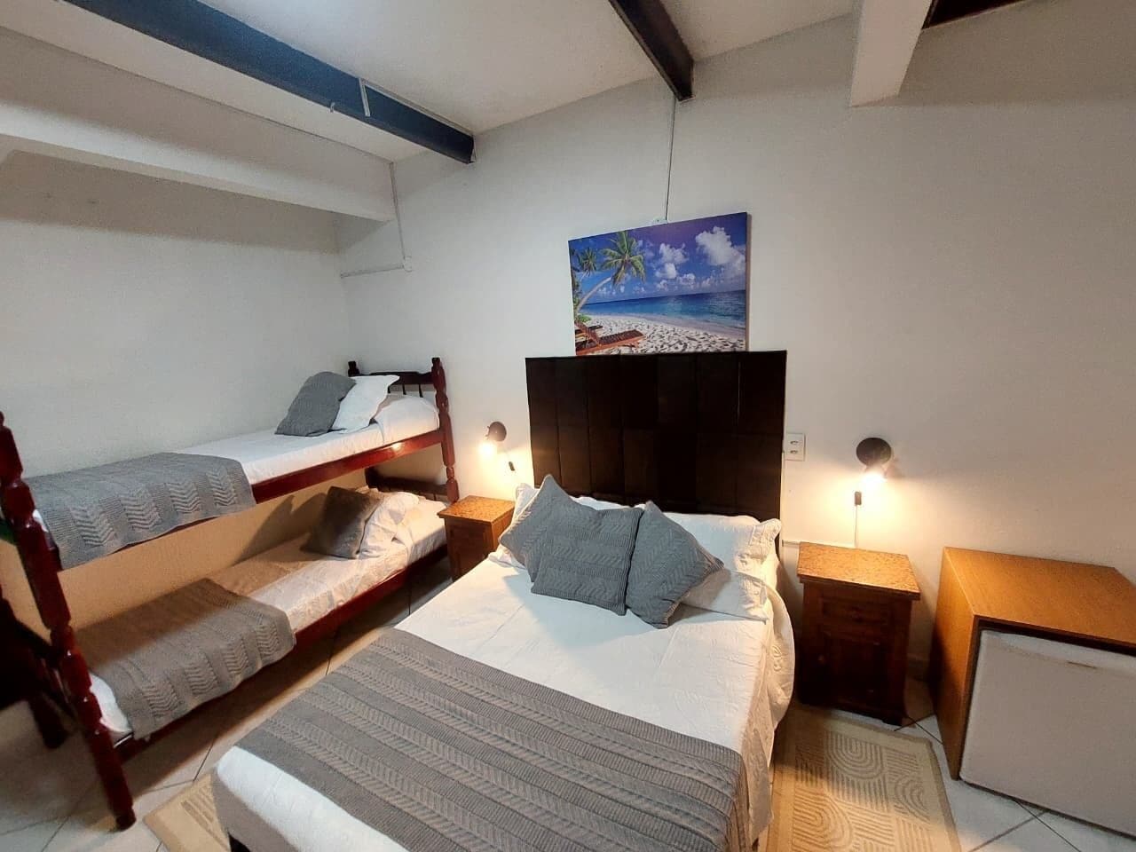 Un dormitorio con literas, una mesita de noche, una lámpara y un cuadro en la pared.
