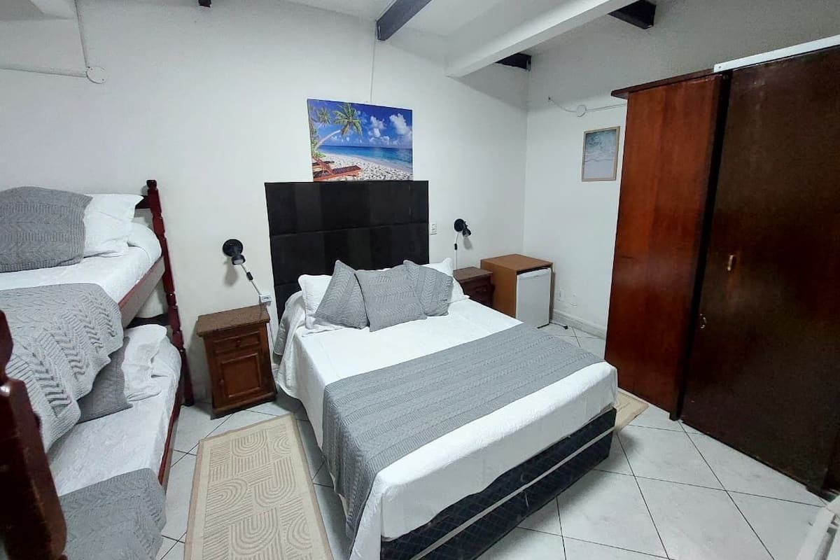 Une chambre à coucher avec un lit, une armoire, une table de chevet, un bureau et un tableau accroché au mur.