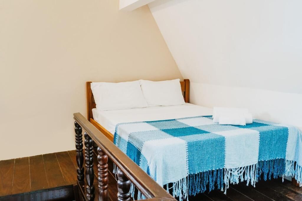 A bedroom with a wooden bed frame, a checkered blanket, and a white pillow.