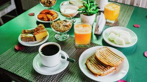 Una mesa dispuesta con alimentos para el desayuno, como tostadas, fruta, cereales, café y jugo.