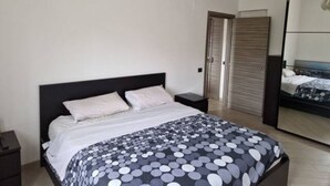 Une chambre à coucher avec un lit, une table de chevet, une armoire et un miroir.