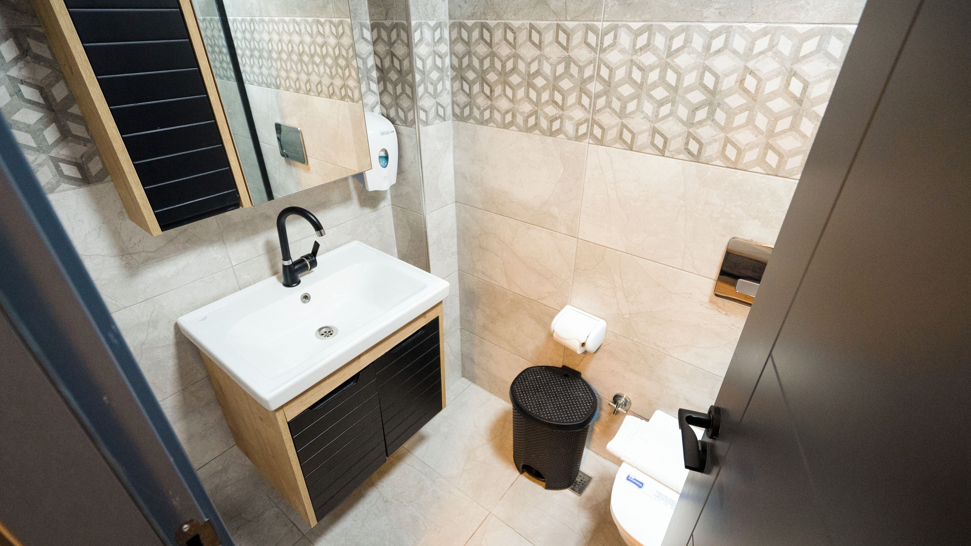 A bathroom with a white sink, black faucet, and a toilet.